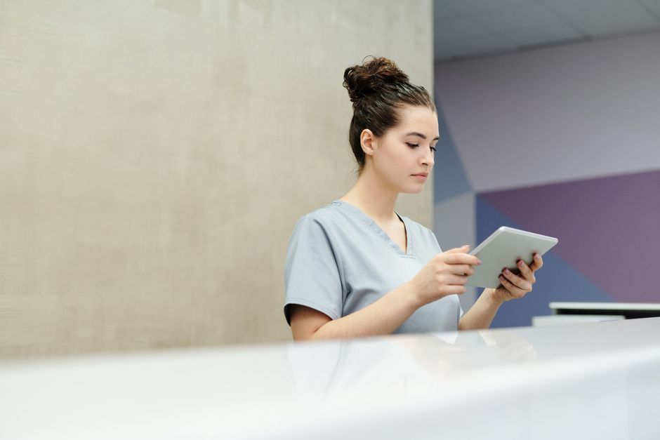 A front-desk staff member preparing the shared tablet for the next patient